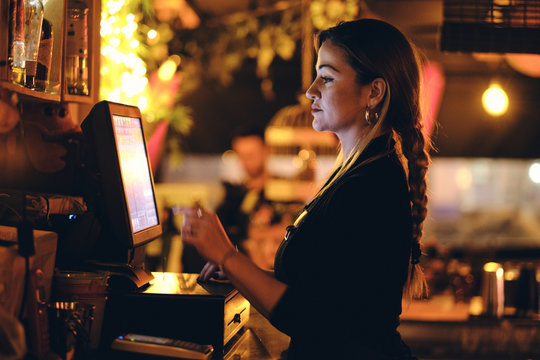 Concepto peque&ntilde;o negocio o emprendimiento personal: una joven camarera en la m&aacute;quina registradora de un bar o restaurante