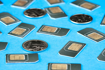 coins and SIM cards are laid out on the blue surface, Russian rubles