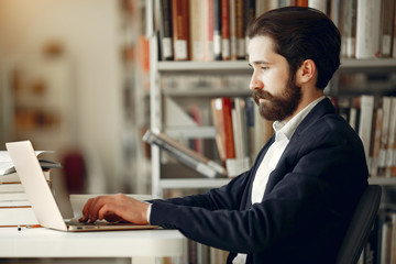 Man in a library. Guy in a black suit. Student with a books.