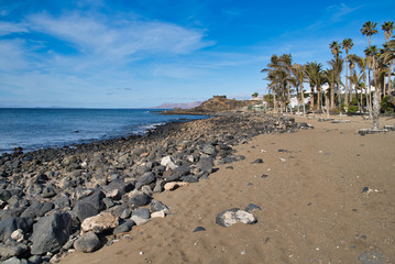 Fototapeta na wymiar Black lava stones on Playa grande in Puerto del Carmen, Lanztarote, Spain