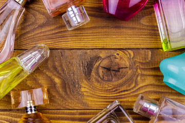 Different bottles of perfume on the wooden background. Top view, copy space