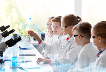 education, science and children concept - kids with test tubes studying chemistry at school...