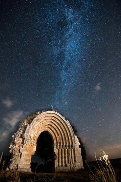 Stars and Milky Way with the ruins of St. Michael arch in Sasamon, Burgos, (Spain) in foreground