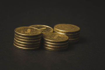 many gold coins lying on top of each other on a black background
