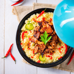 Tajin with couscous, vegetables and meat on white background