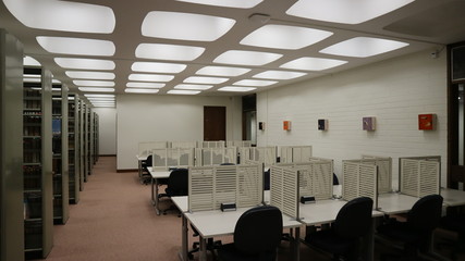 An empty study area with tables and chairs within a university library.
