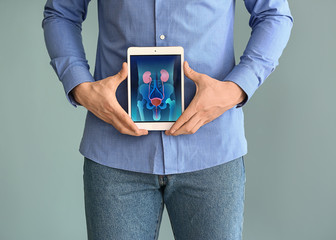 Man holding tablet computer with urinary system on screen against grey background