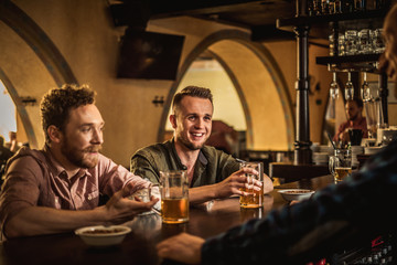Cheerful friends drinking draft beer in a pub