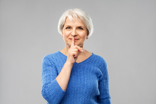 Silence, Censor And Old People Concept - Portrait Of Smiling Senior Woman In Blue Sweater Making Shush Gesture Over Grey Background