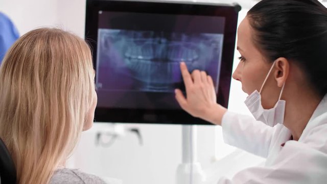 Female dentist pointing at patient's x-ray
