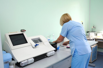 At a hospital laboratory. Lab technician performing analysis of blood samples with gas-electrolyte...