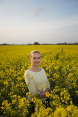 Fototapeta premium Happy woman on blooming rapeseed field in springin yellow blouse.