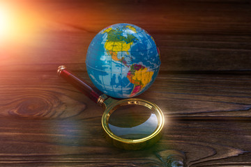 Magnifying glass, globe on wooden background. travel, tourism, active lifestyle