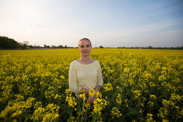 Fototapeta premium Happy woman on blooming rapeseed field in springin yellow blouse.