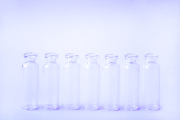 Group Medicine vials with open neck without stopper. Empty glass medical ampoules in a row on a light violet background. Vaccines, Medicine, Immunization concept.