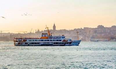 Fototapeta premium Muslim architecture and water transport in Turkey - Beautiful View touristic landmarks from sea voyage on Bosphorus. Cityscape of Istanbul at sunset - old mosque and turkish steamboats, view on Golden