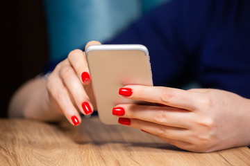 close-up, female hands with red manicure use a smartphone on a white background. Limited depth of field