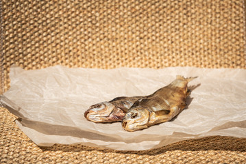 Two dried fish on parchment paper. Selective focus. Copy space.