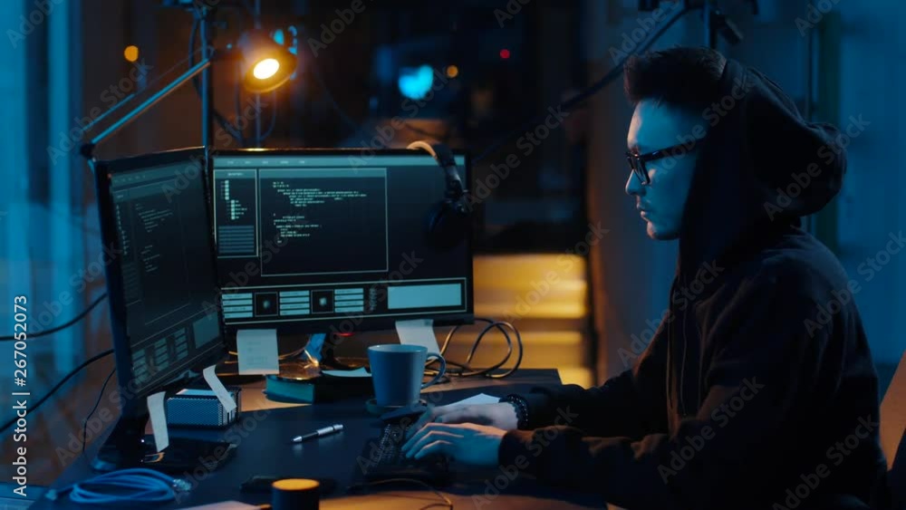 Poster cybercrime, hacking and technology concept - asian male hacker in glasses writing code or using comp