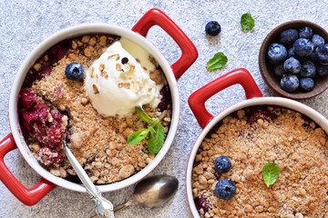 Berry crumble with nuts and ice cream on the kitchen table.