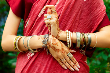 Indian woman with accessories: bracelets and rings wears red inidan paranja doing indian symbol Yin...