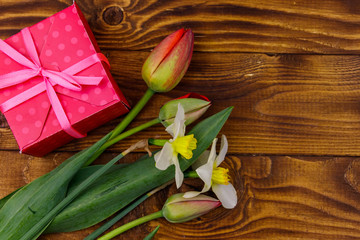 Gift box and bouquet of red tulips and daffodils on wooden background. Concept of Valentine's Day, Women's Day, Mother's Day and Birthday. Top view, copy space