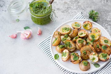 Baked potatoes in rustic style with green pesto sauce