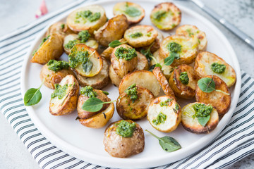 Baked potatoes in rustic style with green pesto sauce