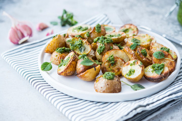 Baked potatoes in rustic style with green pesto sauce
