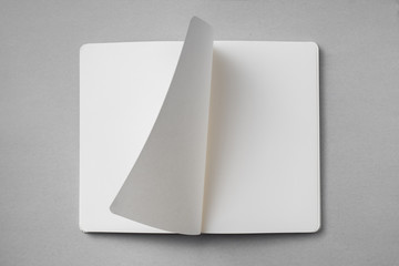 white notebook with turn page on grey background - obrazy, fototapety, plakaty
