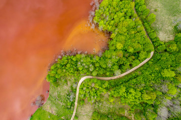 Aerial view of red waste water and green forest