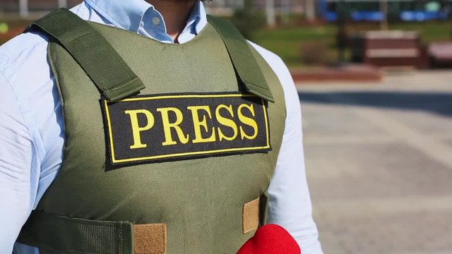 A successful reporter is a man in a bulletproof vest with a microphone in his hands, live on the street, an alarming report.