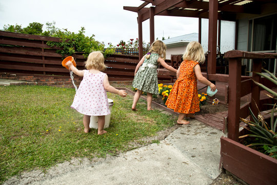 Three gorgeous pre school girls playing in the garden at their Nana's house. Authentic water play in the garden. Dresses made from 1970s fabric upcycled locally. Reduce waste, reuse and repurpose.