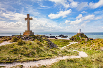 A large Christian cross and Twr Mawr, the old lighthouse on the tidal island of Ynys Llanddwyn,...