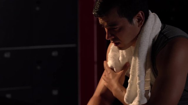 Close-up shot of Handsome athletic man wipes sweat. He tired and muscle weakness after fitness exercise intensive cross. concept of injuries from exercise.