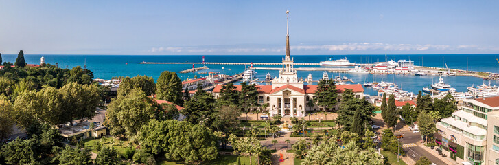 Naklejka na ściany i meble Aerial photography. Panoramic view of the sea port of Sochi on a clear day. Blue sky. Yachts and boats are berthed. Attraction of the resort city.