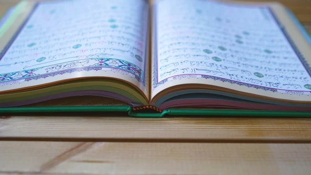 flipping pages of the Quran muslim holy book, detail of surah in slow motion, Holy Quran Kareem on wooden background with copy space, ramadan Kareem concept