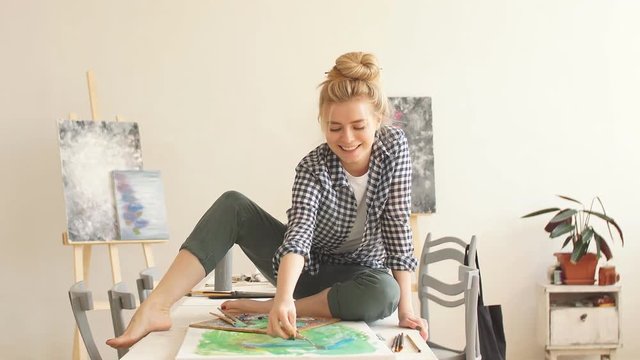 Positive girl in stylish casual clothes working spatula while painting.