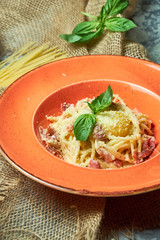 Pasta Carbonara. Gray textured background with beige fabric. Beautiful serving of dishes. Restaurant menu