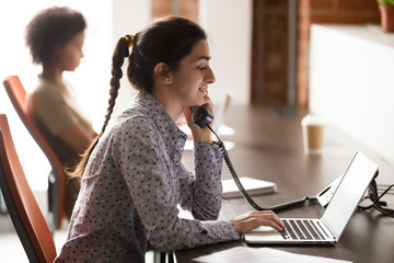 Indian female employee consult client over telephone in office