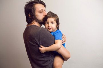 father in the gray shirt holding a son in a blue t-shirt in the hands