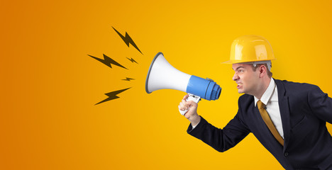 Fototapeta premium Young architect constructor yelling with megaphone and copyspace