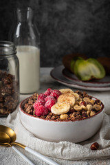 healthy breakfast granola in a plate with nuts, banana and raspberries, copy space