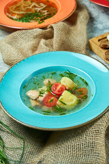 Red fish soup in a blue plate. Beautiful serving dishes. Restaurant menu