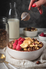 healthy breakfast granola in a plate with nuts, banana and raspberries, copy space