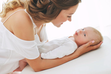 Young mother holding her newborn child. Mom nursing baby. Woman and new born boy relax. Nursery...