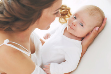 Young mother holding her newborn child. Mom nursing baby. Woman and new born boy relax. Nursery interior. Mother breast feeding baby. Family at home. Portrait of happy mother and baby 