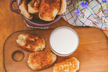 homemade pies in a plate and a glass of milk on a wooden table.