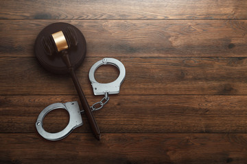 Judge's gavel and handcuffs on wooden background, top view, flat lay. The concept of justice,...
