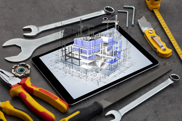 Tablet with construction tools and 3d house plan concept
